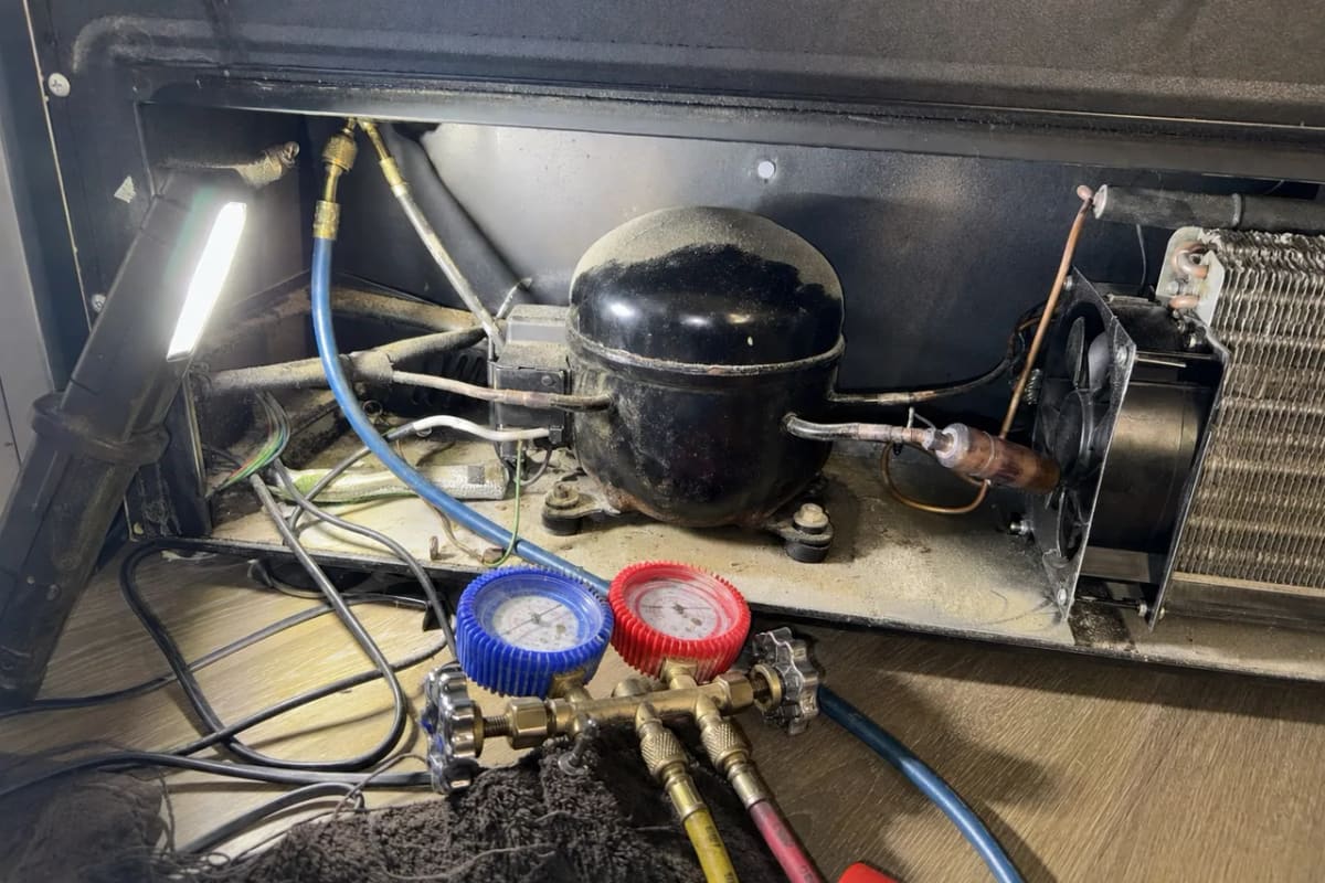 Compressor bay of an under-counter wine cooler with manifold gauges connected