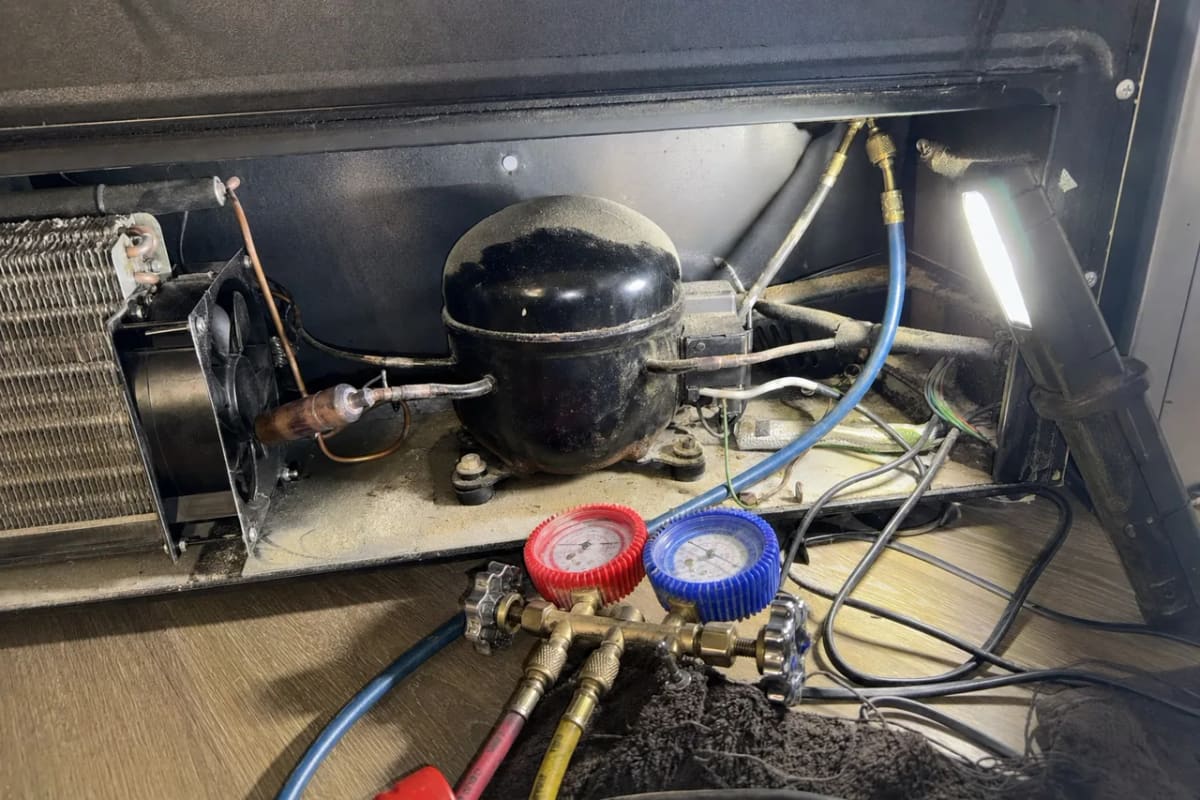 Manifold gauges connected to the compressor bay of a wine cooler during a sealed system test
