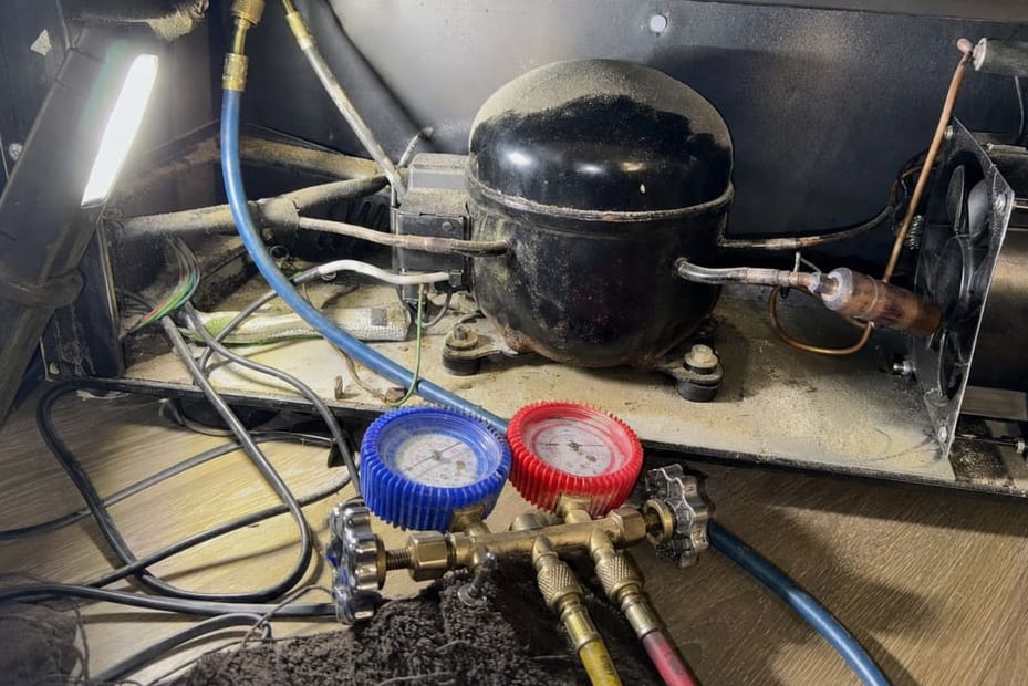 Manifold gauges connected to the compressor and condenser assembly in the lower bay of a wine cooler