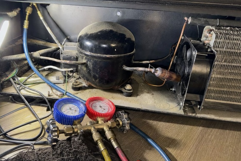 Compressor, condenser fan and refrigerant tubing in the lower bay of a wine cooler