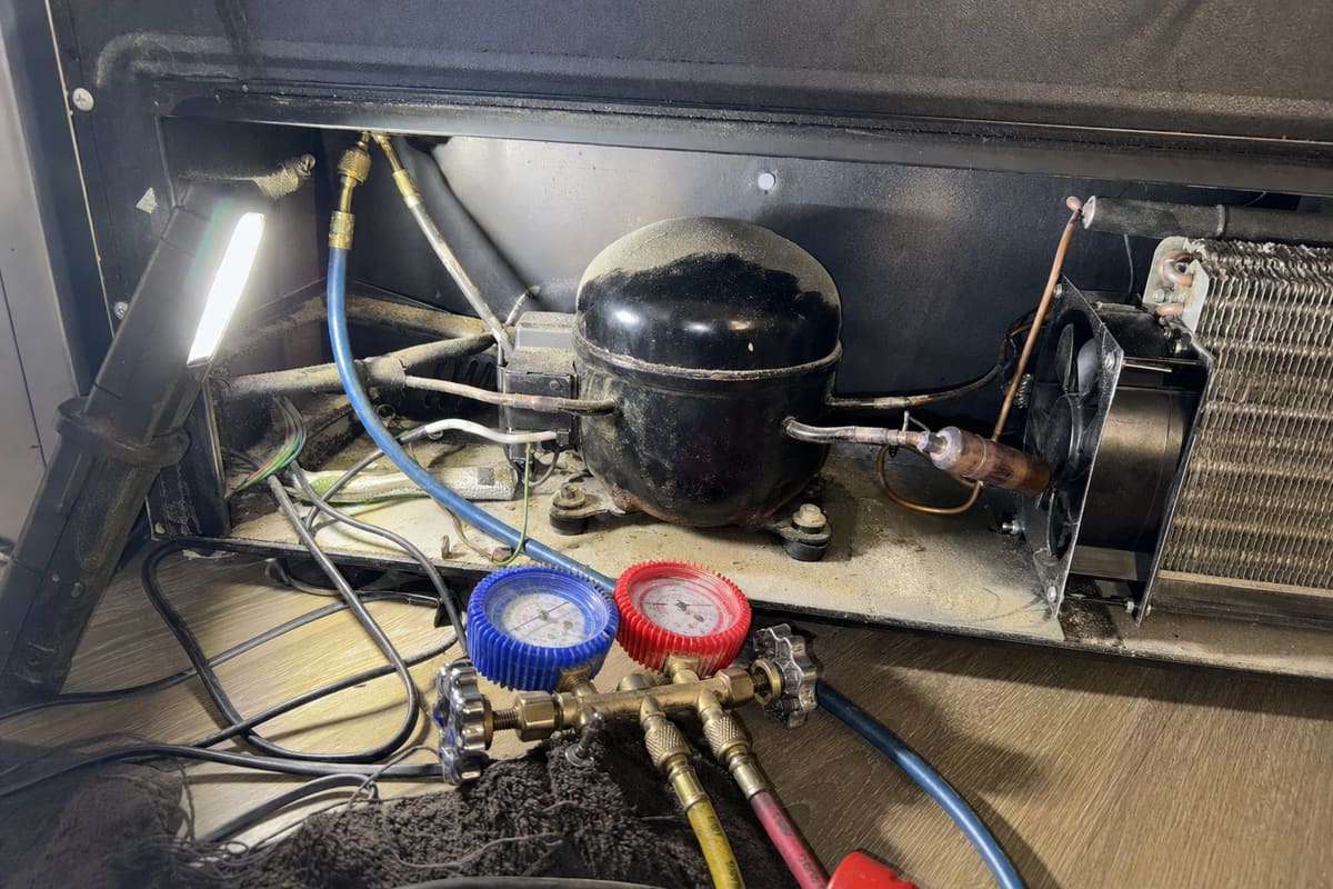 Compressor and condenser fan in the lower bay of a wine cooler with gauges attached