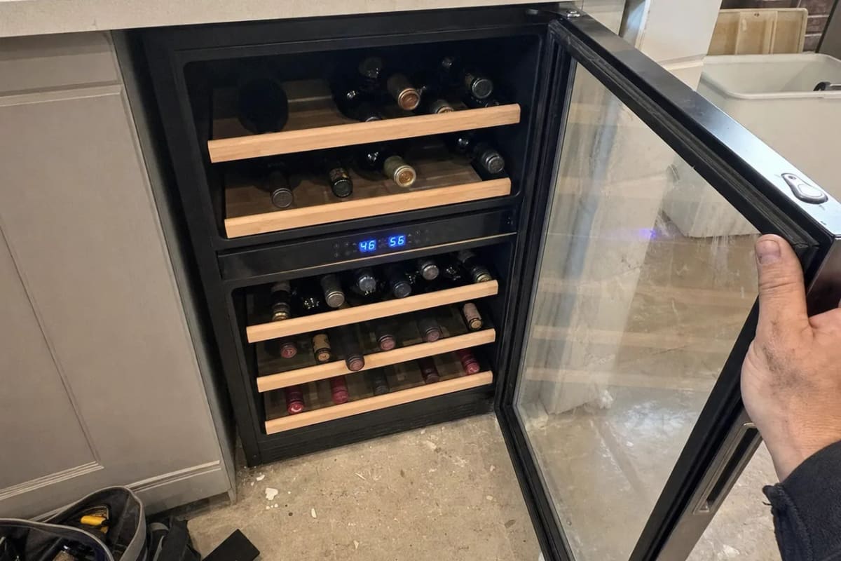 Dual-zone under-counter wine cooler with the glass door open, wooden shelves and a blue LED display between the zones