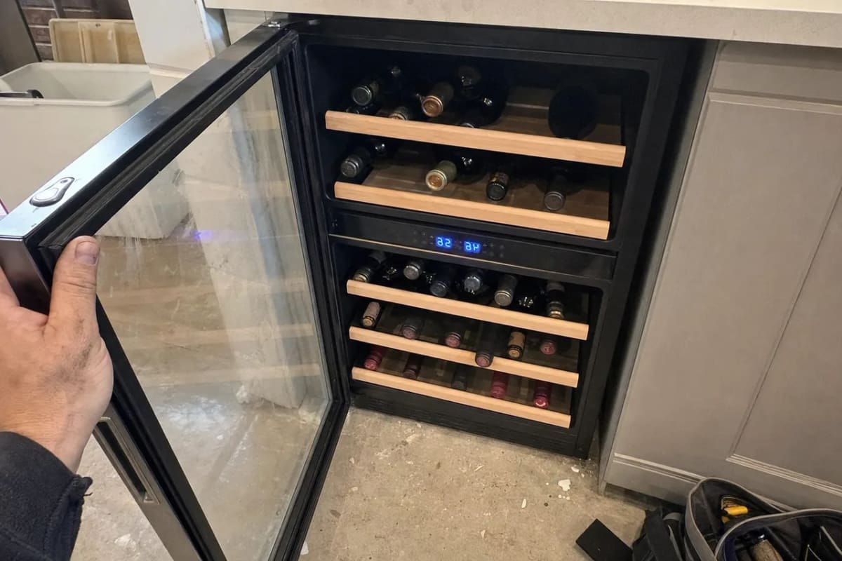 Dual-zone wine cooler open with bottles in both compartments and a blue two-figure temperature display between them