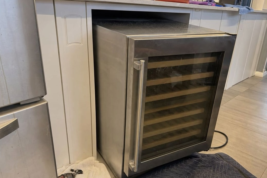 Under-counter wine cooler pulled part way out of its cabinet opening for service